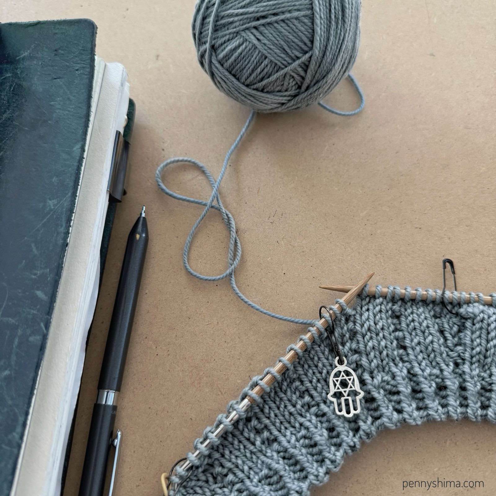 Partial view Mia tee yoke in progress shown in quince sparrow in bird’s egg. Next to a blue traveler’s notebook