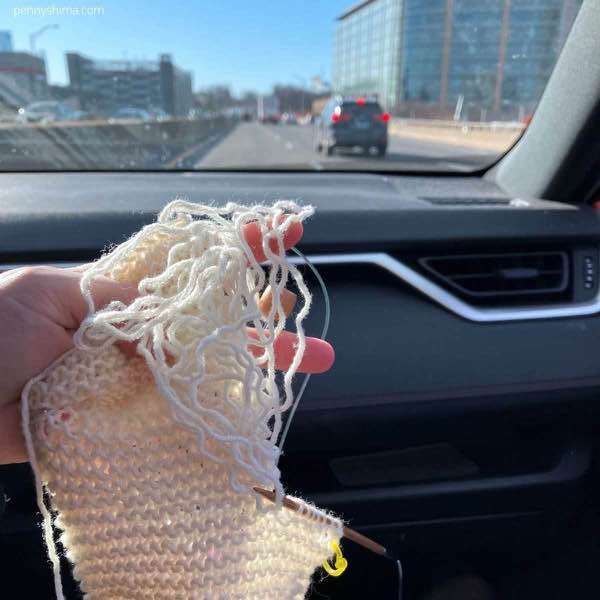 white knit selvedge being repaired held by a hand in the passenger seat of a car