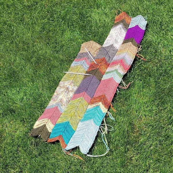 Blanket in progress, laying on a lawn. The third stripe is in progress