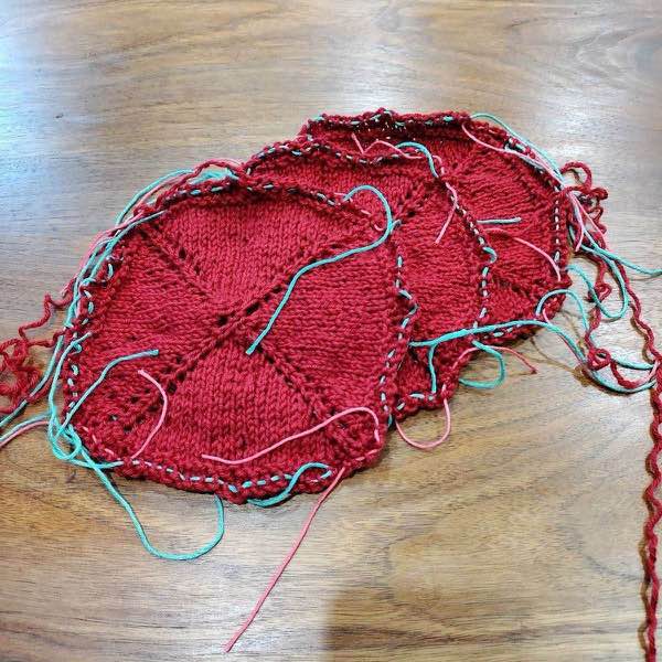 3 squares of red blanket shown fanned on a wooden surface