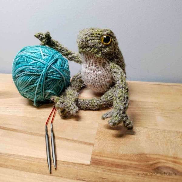 late night finished frog posing next to ball of yarn.