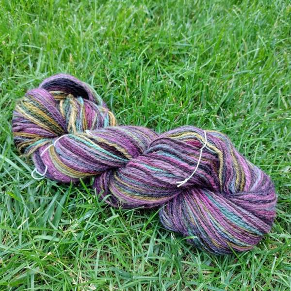 muted autumn rainbow skeined up and laying on green grass.
