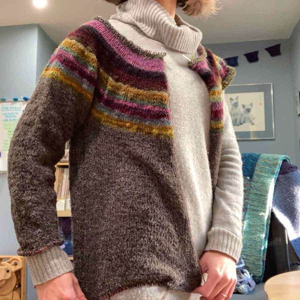 muted rainbow sweater in progress modeled. Part of one sleeve and most of body complete.