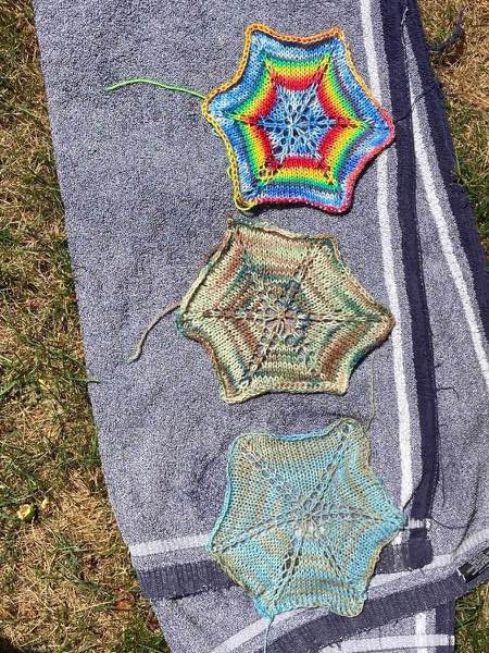 3 hexagons blocking on a blue towel in the sun. One is light blues aand tan, one is blue-greens, and browns (evokes feeling of sea glass), final is rainbow with cloudy blue skies