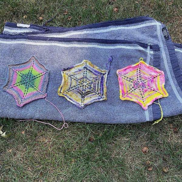 3 hexagons blocking on a blue towel in the sun. 1 is stripes/rings of greens, pink, light purple and tan; 1 is purple, gold, and white; one is fluorescent pink and bright yellow