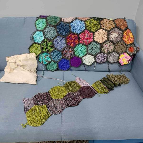 Safe Space blanket on blue couch next to a granny hexagon blanket.
