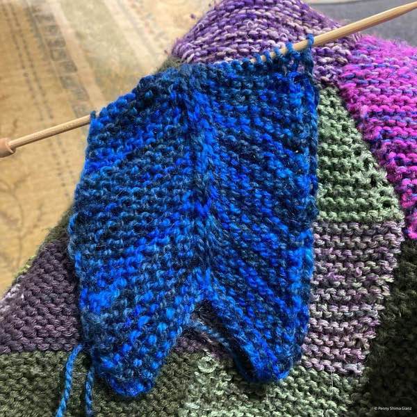 Blue northeasterly blanket in progress about 10cm knitted. Shown on top of the garden for safe space blanket