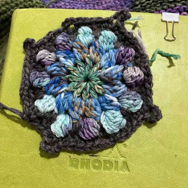 completed crochet motif shown on an anise colored notebook