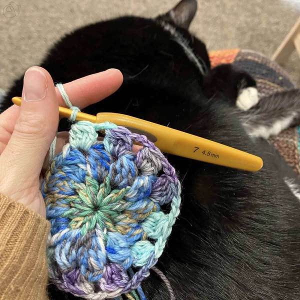 crochet motif in green, blues, aqua and purple in progress.