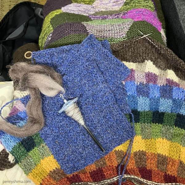 E blue swatches on a sweater in progress with a spindle