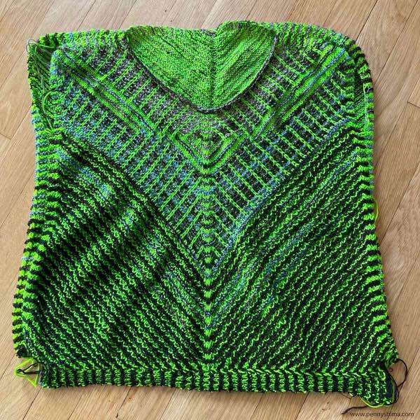 completed knitted on border, front for KAL sweater. it is shown laid flat on a wooden floor.