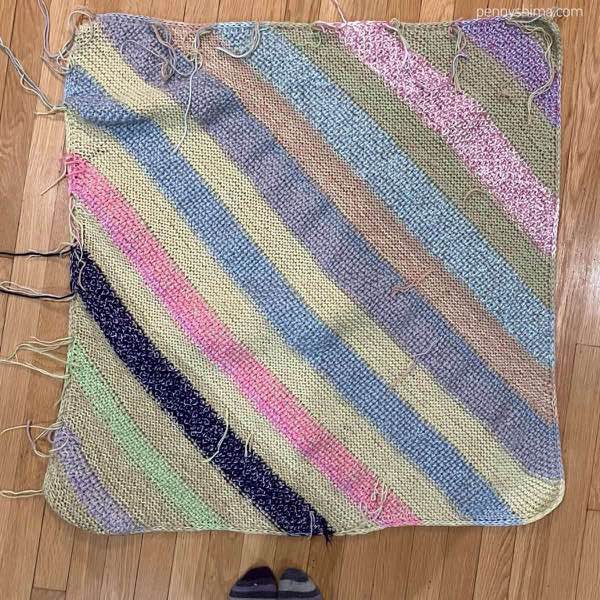 Finished blanket unblocked on a wooden floor, back side view of all the ends