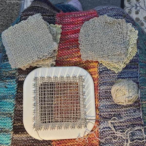 zoom loom with a square in progress and a bunch of squares, shown on a hand knit blanket.